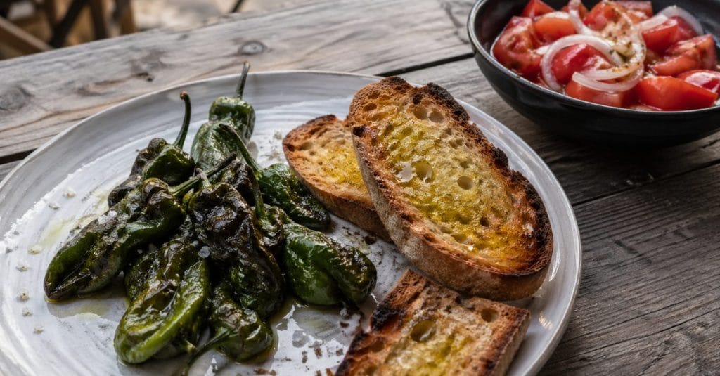 Pimientos del padrón fritos, pan con aceite y ensalada de tomate con cebolla